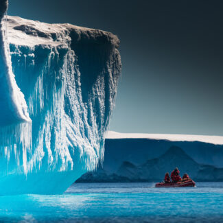 Pequeña embarcación de expedición junto al iceberg